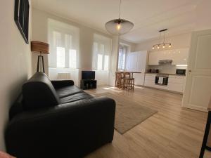 een woonkamer met een zwarte bank en een keuken bij Cosy Appartement 48m Strasbourg Centre et Gare à Pied Proche Musée d Art Moderne Wifi 4 Personnes in Straatsburg +29 foto's