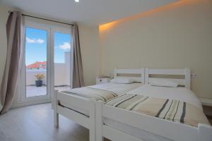a white bedroom with a large bed and a window at Mojo Surf Yoga House in La Orotava