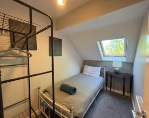 a small bedroom with a bunk bed and a window at Stylish 5BR Townhouse in Manor