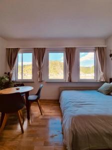 a bedroom with a bed and a table and windows at Rheinromantik mit Blick auf die Burg Katz, bis 4P in Sankt Goar