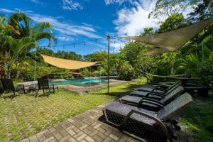 a backyard with a pool and chairs and a hammock at Bamboo River House and Hotel in Dominical