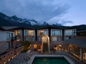 una casa con piscina por la noche con montañas en Lijiang Snow Mountain stone house, en Lijiang