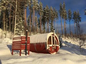 a small house with a snow covered roof next to a bench at Glamping tent in a forest, lake view in Bjuråker +50 photos