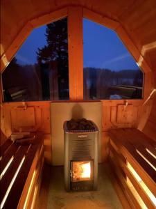 a stove in the middle of a cabin with two benches at Glamping tent in a forest, lake view in Bjuråker