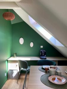 a dining room with green walls and a table and chairs at Les LOTUS de BELLE-YLE in Yvré-lʼÉvêque
