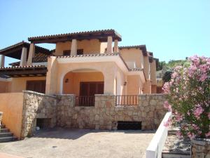 a large house with a stone wall at Case Vacanza Rosa in Porto San Paolo