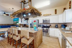 a kitchen with white cabinets and a island with bar stools at Tiki House in Corpus Christi