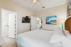 a bedroom with a white bed and a ceiling fan at Tiki House in Corpus Christi +27 photos