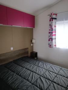 una camera da letto con un letto con armadi viola e una finestra di mobilhome à la mer a Montreuil-sur-Ille