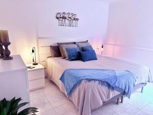 a white bedroom with a large bed with blue pillows at Aquamarina Gran Canaria in Los Caideros +14 photos