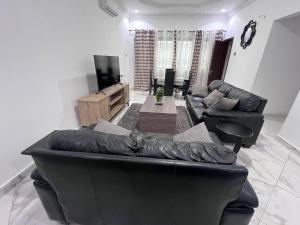a living room with a leather couch and a television at Hearth and Home in Trofwi