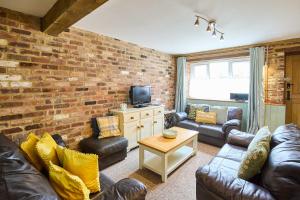 a living room with leather furniture and a brick wall at Host & Stay - West Barn in Toftrees +13 photos