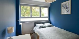 a blue bedroom with a bed and a window at Les portes d'or, appartement Herouville Saint Clair in Hérouville-Saint-Clair