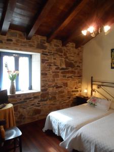 1 dormitorio con 2 camas y pared de piedra en A Cantina, en Mouromorto