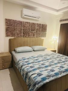 a bedroom with a bed with a blue and white blanket at Apartment in Bahria Town Grand heights 8 Lahore in Lahore