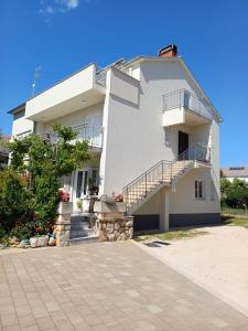 a large white house with stairs and a balcony at Apartment Vidas in Novalja