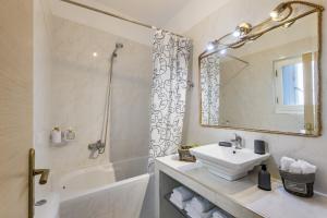 a white bathroom with a sink and a mirror at koukou house skopelos in Skopelos Town +63 photos