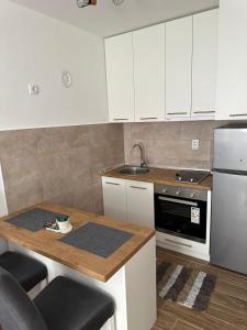 a kitchen with white cabinets and a wooden counter top at Apartment ANDI Istocno Sarajevo in Lukavica +6 photos