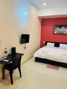 a bedroom with a bed and a desk and a red wall at Alpine Inn in Guwahati +37 photos