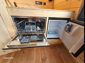 an open refrigerator with a dishwasher in a tiny house at LOGIS LAS CROZAS Le Mousseron orientable in Vernines +30 photos