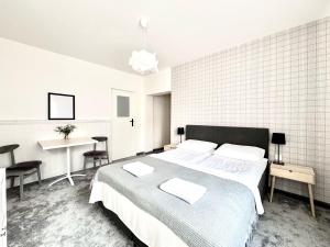 a white bedroom with a large bed and a desk at Biały Domek - STREFA CISZY, CHILDREN FREE in Dźwirzyno