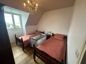 a bedroom with two twin beds and a chandelier at Maison spacieuse et lumineuse à seulement 1 minute de la mer in Rosnoën
