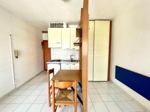 a small kitchen with a table and a refrigerator at Appartamento Celeste I RelaxLagoonView in Lignano Sabbiadoro
