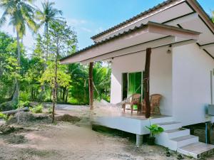 a small white house with two chairs on the porch at Suanthara kokut in Ko Kood