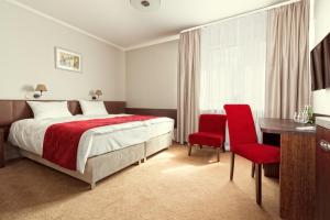 a bedroom with a bed and a desk and red chairs at Maestro Inn in Krasnystaw