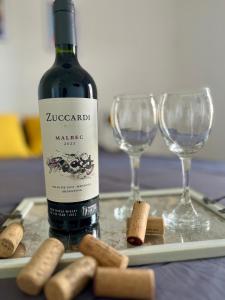 a bottle of wine and two wine glasses on a tray at Departamento céntrico y moderno a pasos de Plaza España, en pleno microcentro de Mendoza!! Pellegrini Apartments Rivadavia in Mendoza