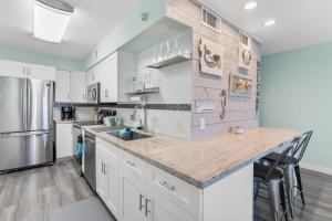 a kitchen with white cabinets and stainless steel appliances at Sandy Paws in Navarre +21 photos