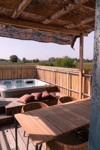 a deck with a hot tub and tables and chairs at Au Chai Bigaroux Saint-Emilion in Saint-Sulpice-de-Faleyrens