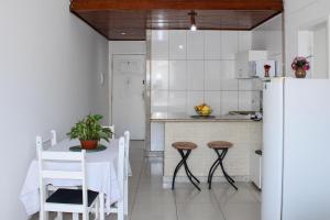 a kitchen with a table and a white refrigerator at Apartamento Farol Barra Flat in Salvador