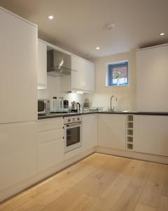 a kitchen with white cabinets and a wooden floor at Citystay - Pringle House in Cambridge