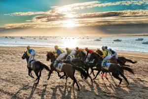 eine Gruppe von Menschen, die am Strand reiten in der Unterkunft Casa Lotte, centro histórico,AC, garaje, wifi in Sanlúcar de Barrameda