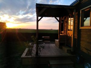 a sunset from the porch of a cabin with a table and chairs at Tiny House Min puppa proche Baie de Somme in Quesnoy-le-Montant