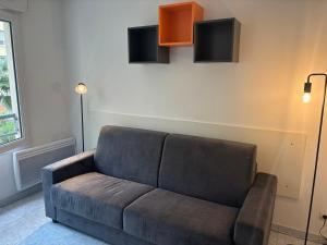 a couch in a living room with a tv on the wall at Studio Calif, face tram proche Mer in Nice