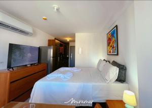 a bedroom with a white bed and a flat screen tv at Simple Smart Residence in Tambaú