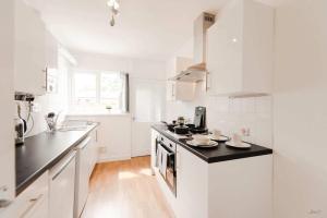 a white kitchen with white cabinets and black counter tops at Peaceful Room in Doncaster Shared House w Kitchen in Doncaster +8 photos