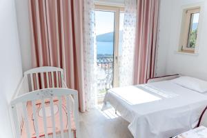 a bedroom with a crib and a bed and a window at Three Bedroom Family Apartment - Lustica Marina Village in Radovići