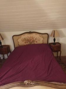 a bed with a purple blanket and two night stands at Happy Homes in Plouyé