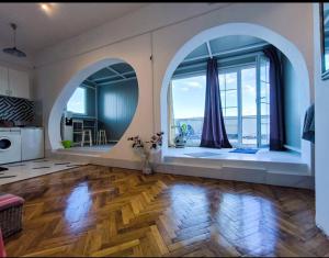 Una gran sala de estar con una ventana arqueada y pisos de madera. en on top of the city, en Belgrado