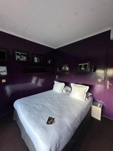 a bedroom with a large white bed with purple walls at Hotel Ermitage in Saint-Tropez
