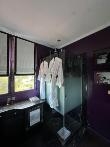 a bathroom with a shower and two shirts on hangers at Hotel Ermitage in Saint-Tropez