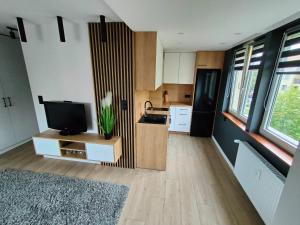 a living room with a television and a kitchen at Apartament w Centrum in Suwałki