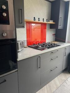 a kitchen with a stove and a red window at Modern flat in quiet residential cul-de-sac in Kilwinning