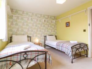 two beds in a room with yellow walls at Jasmine Cottage in Bakewell