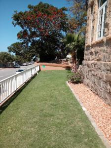 a yard of grass next to a building with a fence at Twin Palms Accommodations in Mossel Bay +19 photos
