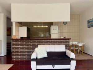 a white couch in a room with a kitchen at La Bocca Apartment - Sarajevo Airport, Private Parking, 2 ACs in Sarajevo