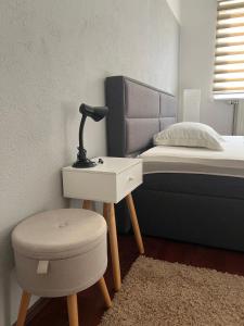 a bedroom with a bed with a lamp and a stool at La Bocca Apartment - Airport, Parking, AC, Bidet, Coffee Machine, PS3 in Sarajevo